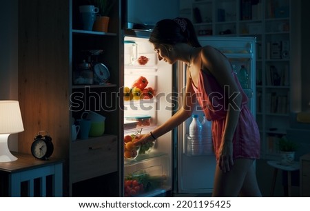 Young woman looking in the fridge at night, she is hungry Royalty-Free Stock Photo #2201195425
