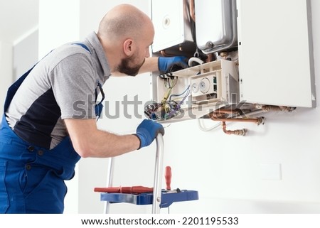 Professional boiler service: qualified technician checking a natural gas boiler at home Royalty-Free Stock Photo #2201195533