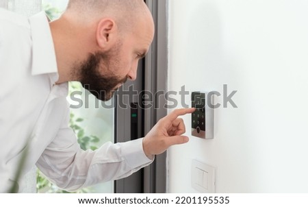 Man setting an alarm code for home security, alarm system concept Royalty-Free Stock Photo #2201195535