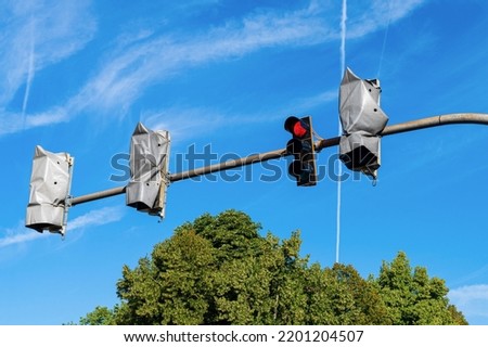 Street traffic lights on a horizontal bar under the blue sky. Three of them are non-working, wrapped with foil.