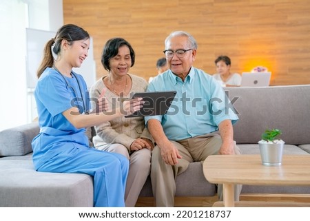 Beautiful Asian nurse or doctor use tablet to consult and give assistant to couple senior man and woman in living room of clinic or hospital in senior healthcare center. Royalty-Free Stock Photo #2201218737