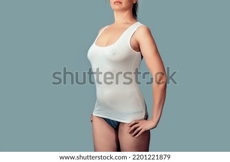 Stunning Slim Woman in White T-Shirt with Straight Hair Standing on Gray Background. Top-Rated Image with Perfect Body Shape, Fitness and Health Concept