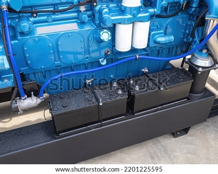 Equipment for sea vessels. River engine next to batteries. Lead batteries next to blue motor. Blue engine for river or sea vessels. New engine for small ship. Spare parts for motor boats Royalty-Free Stock Photo #2201225595