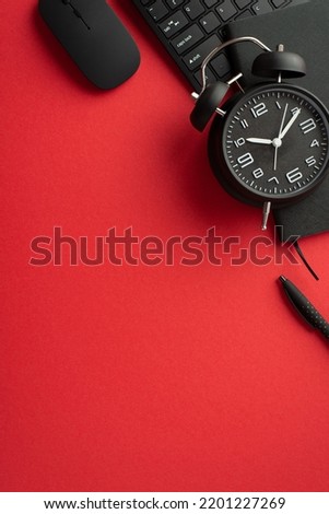 Black friday sale concept. Top view vertical photo of black alarm clock notepad pen computer mouse and keyboard on isolated red background with empty space
