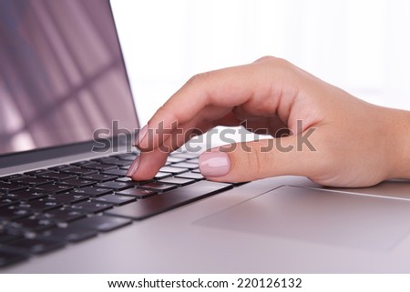 Female hands working on laptop on light background