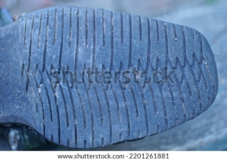 part of the boot with a rubber dirty old sole with a black pattern on a gray background
