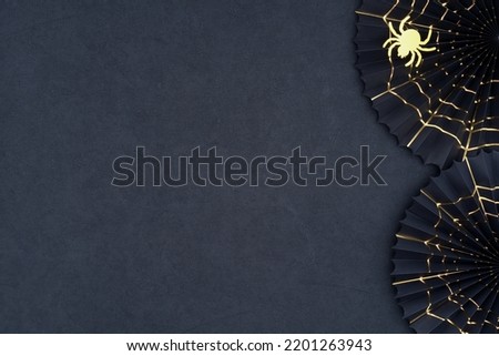 Spider and cobweb Halloween decoration background. The scary Halloween paper fans with gold cobwebs as a border on a dark textured background. Halloween theme with copy space. Royalty-Free Stock Photo #2201263943