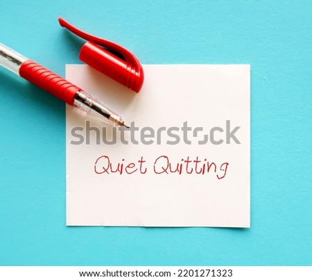Pen on blue background with handwritten text QUIET QUITTING, workplace buzzword of employees  limited tasks, avoid working long hours, to set clear boundaries to improve work life balance Royalty-Free Stock Photo #2201271323