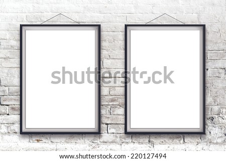 Two blank vertical painting poster in black frame hanging on white brick wall. Painting proportions match international paper size A.