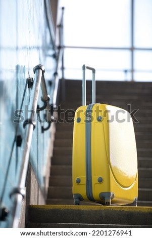 close-up photo of yellow suitcase on the stairs at the airport while waiting to fly
