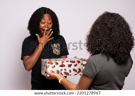african lady receiving a gift from a friend, looks surprised