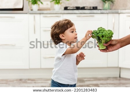 The Black one year child eats broccoli with an appetite. Organic Cabbage and food. Green healthy vegetables rich in vitamins. Proper nutrition concept. Royalty-Free Stock Photo #2201283483
