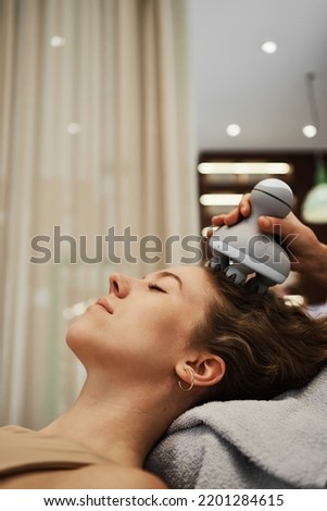 The master massages the woman's head using a gadget. High quality photo