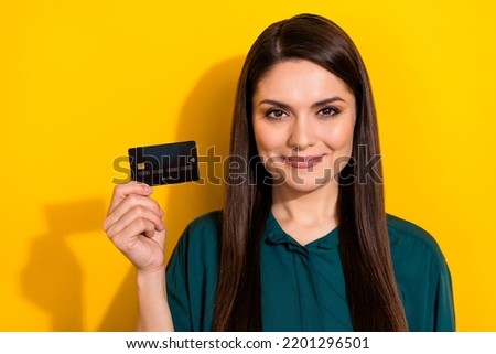Photo of young pretty woman hold bank card salary income earnings isolated over yellow color background