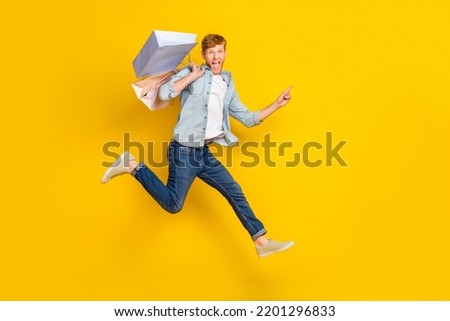 Full length photo of handsome guy dressed blue shirt denim jeans scream directing empty space flying isolated on yellow color background