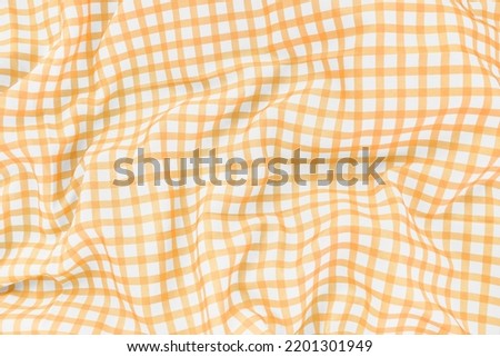 Yellow checkered picnic tablecloth as background, top view
