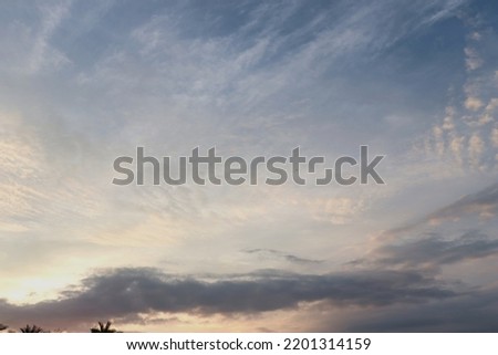 A beautiful sky painted by the sun leaving vibrant gold and pink hues. Clouds in the twilight sky, in the evening. Image of a cloudy sky in the evening. Evening sky scene with golden light.