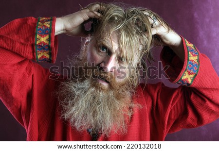 close-up portrait of the blessed with a long beard and a mustache and wet blond hair in a red shirt studio