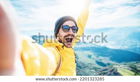 Handsome man taking selfie picture on top of mountains - Happy hiker smiling at camera trekking outside - Traveler lifestyle, hiking and sport concept