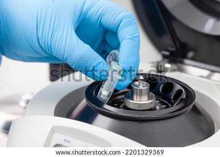 Closeup of a scientist hand placing a tube into an small table centrifuge. Spin column-based nucleic acid purification technique. Diagnosis of human papillomavirus virus infection.