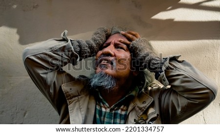 Close Up The face of a dirty-dressed, long-haired, long-haired old man, who is homeless, is showing signs of serious stress because he has no food to eat and no work to sleep on the streets.