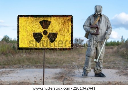 Old textural sign of radiation hazard, military chemical reconnaissance measures the level of radiation against the background of contaminated nature.