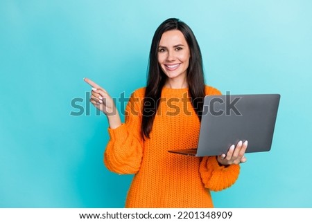 Photo of girlish cheerful woman with long hairstyle wear pullover directing empty space hold laptop isolated on turquoise color background