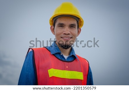 Confident young Asian engineer, Construction manager in reflective clothing and helmet, smiling face, confident in quality, Concept of construction and industrial workers.