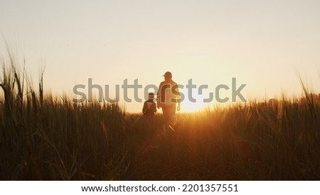 Farmer and his son in front of a sunset agricultural landscape. Man and a boy in a countryside field. Fatherhood, country life, farming and country lifestyle. Royalty-Free Stock Photo #2201357551