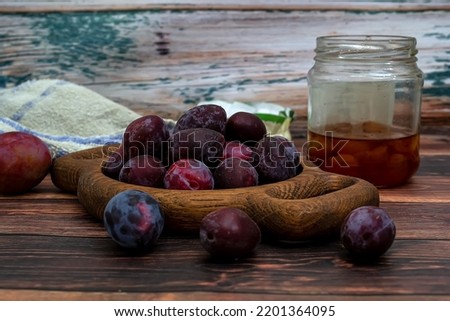 Fresh ripe plums with leaves in a basket on a wooden table