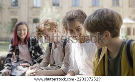 Happy multiethnic school friends talking and laughing during break, having fun Royalty-Free Stock Photo #2201372529