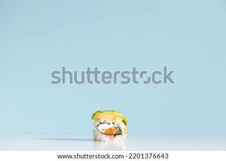 Sushi roll over blue background. Sushi roll with eel, tofu, vegetables and avocado closeup.