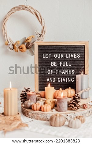 Felt letter board and text let our lives be full of thanks and giving. Autumn table decoration. Interior decor for thanksgiving and fall holidays with handmade pumpkins and candles