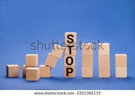 Stop wording print on wooden block cube protect wooden falling domino for risk management concept.