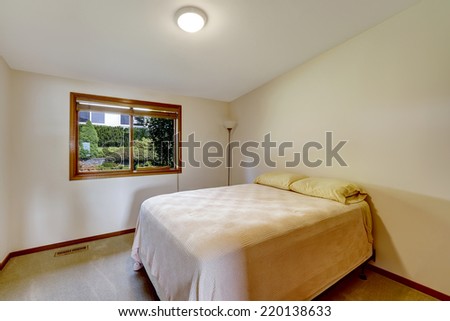 Simple bedroom with vaulted ceiling and window. Old bed with a lamp
