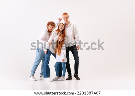 Happy family, red-haired young men, woman and kid wearing casual style clothes spend time together at studio photo shoot. Look delighted, thrilled. Concept of emotions, love, fashion, relationship