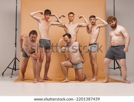 Diversity. Young cheerful people, men of different body types standing together in underwear at studio photo shoot. Concept of emotions, body positive, fashion, friendship. Model posing, having fun Royalty-Free Stock Photo #2201387439