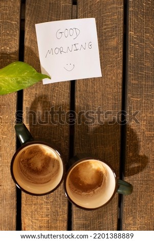 
Good morning note "good morning", two empty coffees and heart shadow on wood. Loving couple morning