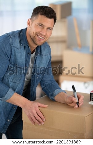 warehouse manager writing on a card box