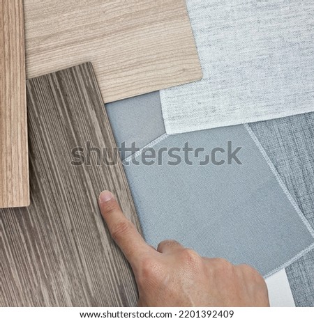 interior architect selecting combination of interior material samples including grey drpaery fabric samples, Italian walnut veneer, oak laminateds for selection for Scandinavian interior style.