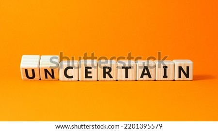 Certain or uncertain symbol. Turned wooden cubes and changed the concept word uncertain to certain. Beautiful orange table, orange background, copy space. Business, certain or uncertain concept.