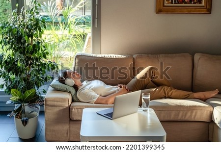 Young woman having online hypnotherapy regression session with psychotherapist lying on sofa at home. Digital service Royalty-Free Stock Photo #2201399345