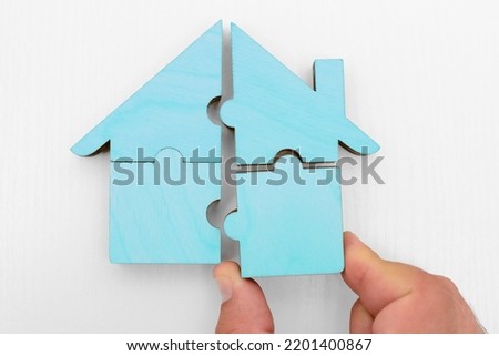 hand holds pieces of blue wooden house puzzle isolated on white  background. wooden home made from natural material of jigsaw. puzzle in the form of wood house. for sale or rent. concept of mortgage