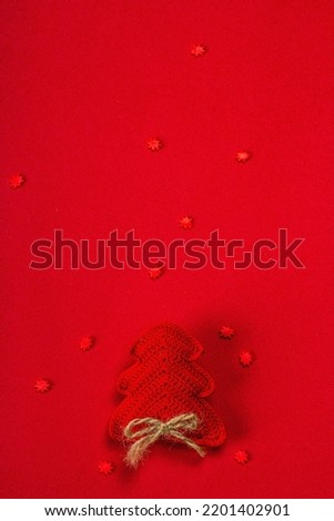 New Year or Christmas background. Handmade crocheted fir tree, sweet snowflakes on red rough background. Minimalistic monochrome design, flat lay