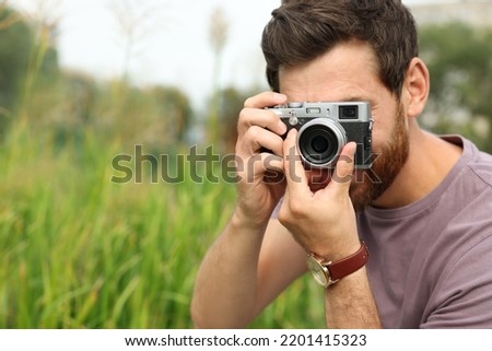 Man with camera taking photo outdoors, space for text. Interesting hobby