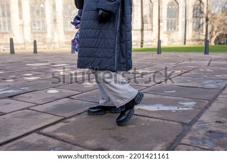 feet of a woman in a black shoes  on the city street on cold day