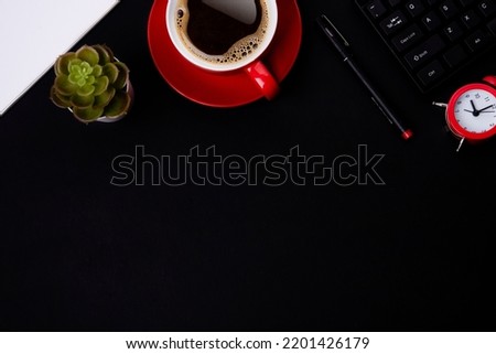 red cup of coffee, pen, glasses, alarm,  plant, phone, and paper on a black background  as workplace top view space for text
