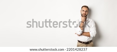 Thoughtful businessman in glasses making plan, looking at upper left corner and thinking, standing against white background Royalty-Free Stock Photo #2201428237
