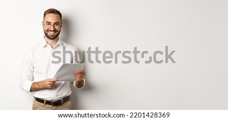 Employer looking satisfied with work, reading documents and smiling pleased, standing over white background