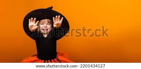 Celebrating Halloween. Little girl dressed as a witch holds a bucket of pumpkins on a yellow background.banner